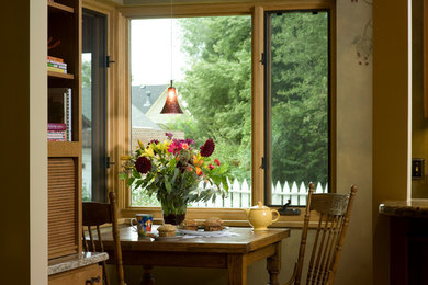 Ejemplo de despacho de estilo de casa de campo pequeño con paredes verdes, suelo de madera clara y escritorio empotrado