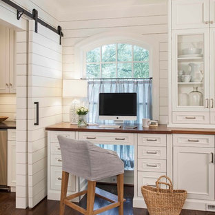 Elegant built-in desk dark wood floor home office photo in Charlotte with white walls