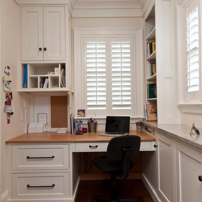 Inspiration for a timeless built-in desk dark wood floor home office remodel in Other with white walls