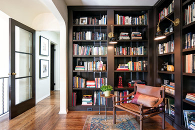 Imagen de despacho mediterráneo de tamaño medio con biblioteca, suelo de madera en tonos medios, suelo naranja y paredes blancas
