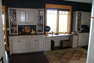 Diseño de despacho rústico de tamaño medio con paredes azules, suelo de madera oscura, escritorio empotrado y suelo negro