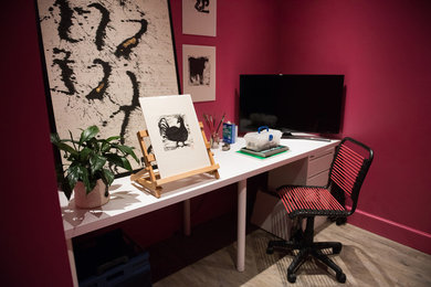 Ejemplo de estudio ecléctico de tamaño medio sin chimenea con paredes rojas, suelo de madera clara y escritorio independiente