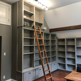 Cette image montre un bureau craftsman de taille moyenne avec un mur gris, un sol en bois brun et un sol rouge.