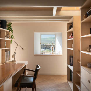 Small scandi study in London with white walls, light hardwood flooring, no fireplace, a built-in desk, brown floors and exposed beams.