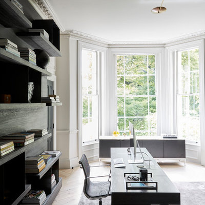Example of a large trendy freestanding desk light wood floor study room design in London with white walls