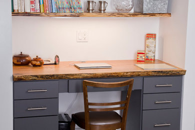 Ejemplo de despacho de estilo americano pequeño sin chimenea con paredes blancas, suelo de madera en tonos medios y escritorio empotrado