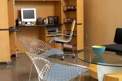Ejemplo de despacho contemporáneo grande sin chimenea con paredes amarillas, suelo de cemento y escritorio independiente