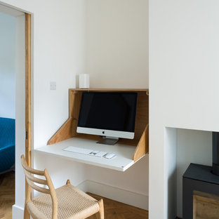 Kleines Stilmix Arbeitszimmer mit weißer Wandfarbe, hellem Holzboden, Kaminofen und braunem Boden in London