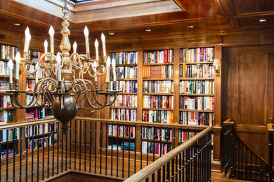 На фото: огромный домашняя библиотека в стиле неоклассика (современная классика) с коричневыми стенами, паркетным полом среднего тона и встроенным рабочим столом без камина