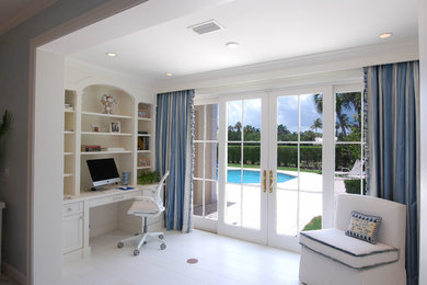 Home office - traditional built-in desk painted wood floor and white floor home office idea in Miami with white walls