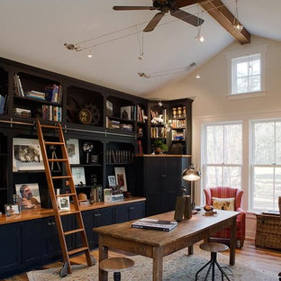 Großes Rustikales Arbeitszimmer mit weißer Wandfarbe, braunem Holzboden und freistehendem Schreibtisch in Charleston