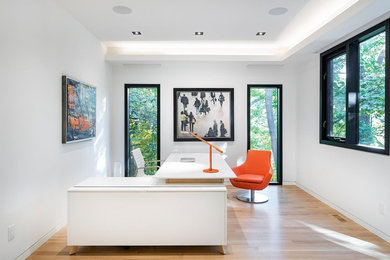 Modernes Arbeitszimmer ohne Kamin mit Arbeitsplatz, weißer Wandfarbe, hellem Holzboden, freistehendem Schreibtisch und beigem Boden in Toronto