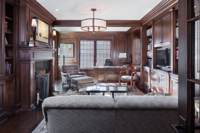 Large classic study in Boston with brown walls, dark hardwood flooring, a standard fireplace, a wooden fireplace surround and a built-in desk.