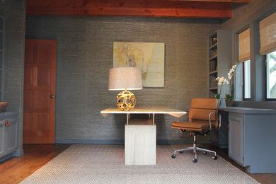 Cette photo montre un bureau tendance de taille moyenne avec un sol en bois brun, aucune cheminée, un bureau indépendant et un mur gris.