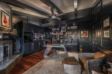 フェニックスにあるコンテンポラリースタイルのおしゃれなホームオフィス・書斎 (黒い壁、濃色無垢フローリング、コーナー設置型暖炉、タイルの暖炉まわり、自立型机、茶色い床) の写真