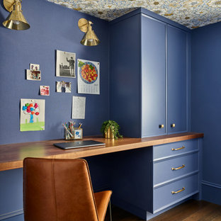 Großes Klassisches Arbeitszimmer ohne Kamin mit Arbeitsplatz, blauer Wandfarbe, braunem Holzboden, Einbau-Schreibtisch, braunem Boden, Tapetendecke und Wandpaneelen in Manchester
