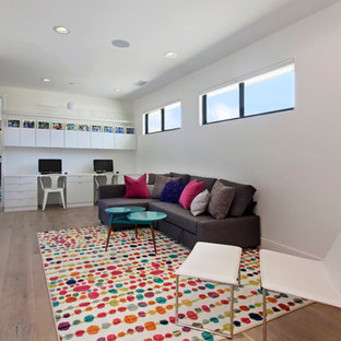 This is an example of a large contemporary study room in Orange County with white walls, light hardwood floors, no fireplace and a built-in desk.