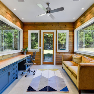 Klassisches Arbeitszimmer ohne Kamin mit Arbeitsplatz, brauner Wandfarbe, Einbau-Schreibtisch, grauem Boden und Holzwänden in Austin