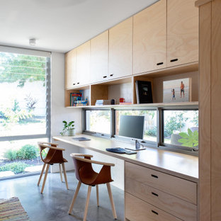 This is an example of an industrial home office in Perth with white walls, concrete floors, a built-in desk and grey floor.