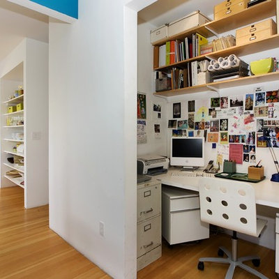 Trendy built-in desk medium tone wood floor home office photo in San Francisco with white walls