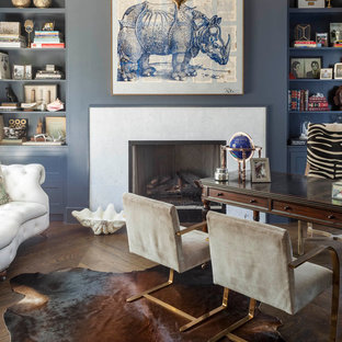 Modernes Arbeitszimmer mit Arbeitsplatz, blauer Wandfarbe, dunklem Holzboden, Kamin, Kaminumrandung aus Stein und freistehendem Schreibtisch in Dallas