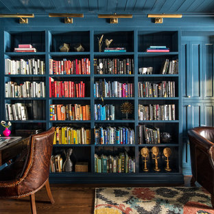 Bild på ett vintage arbetsrum, med ett bibliotek, blå väggar, mörkt trägolv och ett fristående skrivbord