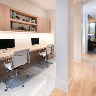 Cette image montre un bureau design de taille moyenne avec un mur blanc, un bureau intégré et un sol blanc.