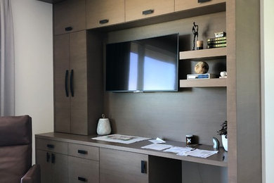 Modelo de despacho moderno de tamaño medio con paredes blancas, suelo de madera clara, escritorio empotrado y suelo marrón