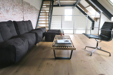 Photo of a large industrial home studio in Amsterdam with white walls, light hardwood flooring, no fireplace, a freestanding desk and brown floors.