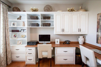 Modelo de despacho clásico con paredes blancas, escritorio empotrado y suelo de madera en tonos medios