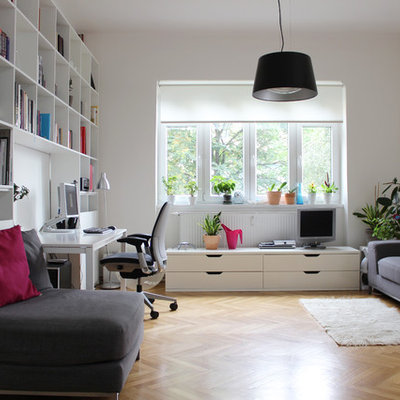 Trendy freestanding desk medium tone wood floor and beige floor home office photo in Other with white walls