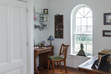 Idéer för små vintage hemmabibliotek, med vita väggar, mörkt trägolv och ett fristående skrivbord