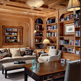 Mittelgroßes Klassisches Arbeitszimmer mit beiger Wandfarbe, dunklem Holzboden, braunem Boden, Arbeitsplatz, freistehendem Schreibtisch, Kamin und gefliester Kaminumrandung in Charlotte