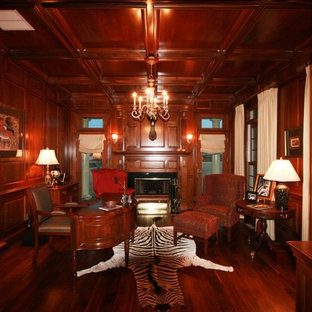 Exemple d'un bureau chic de taille moyenne avec un sol en bois brun, une cheminée standard, un manteau de cheminée en pierre, un bureau indépendant, un mur rouge et un sol rouge.