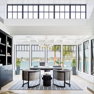 Cette photo montre un très grand bureau bord de mer avec un mur blanc, un sol en bois clair, un bureau indépendant et un sol beige.
