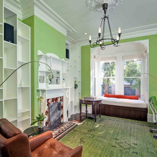 Diseño de despacho clásico renovado con paredes verdes, suelo de madera oscura, marco de chimenea de baldosas y/o azulejos, escritorio independiente y suelo verde