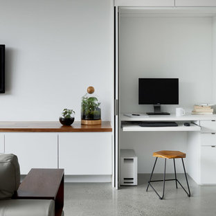 Exempel på ett mellanstort modernt arbetsrum, med vita väggar, betonggolv, ett inbyggt skrivbord och grått golv