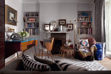 ロンドンにある高級な中くらいなエクレクティックスタイルのおしゃれなホームオフィス・書斎 (グレーの壁、淡色無垢フローリング、標準型暖炉、木材の暖炉まわり、自立型机) の写真