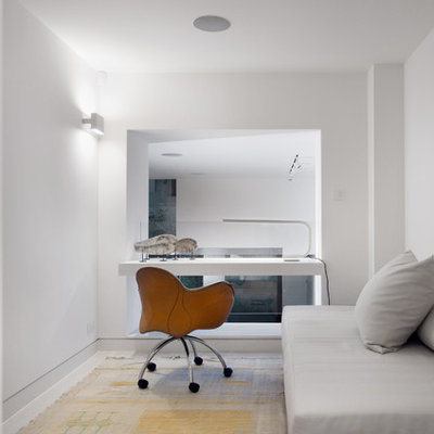 Mid-sized trendy built-in desk study room photo in London with white walls