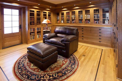 Foto de despacho de estilo americano de tamaño medio con biblioteca, paredes marrones, suelo de madera clara, escritorio independiente y suelo marrón