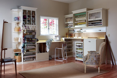 Modelo de sala de manualidades contemporánea de tamaño medio sin chimenea con paredes beige, suelo de madera clara, escritorio empotrado y suelo marrón