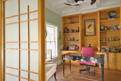 На фото: домашняя библиотека среднего размера в восточном стиле с зелеными стенами, полом из винила, отдельно стоящим рабочим столом и коричневым полом без камина с