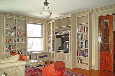 Example of a large classic medium tone wood floor study room design in Bridgeport with white walls