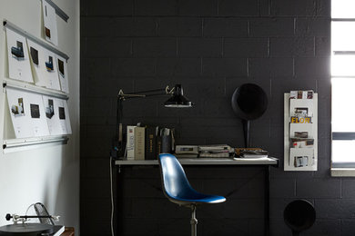 Esempio di uno studio industriale con pareti nere, pavimento in cemento, scrivania autoportante e pavimento grigio
