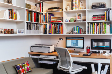 Exempel på ett modernt hemmabibliotek, med heltäckningsmatta, ett inbyggt skrivbord och vita väggar