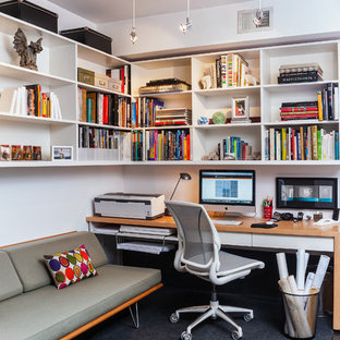 Exempel på ett modernt hemmabibliotek, med heltäckningsmatta, ett inbyggt skrivbord och vita väggar