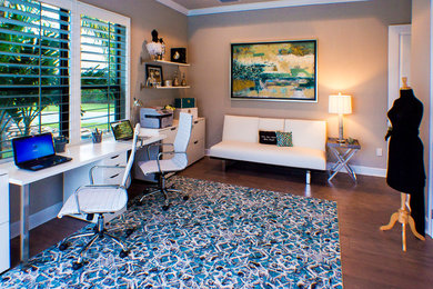 Mittelgroßes Modernes Arbeitszimmer mit Arbeitsplatz, grauer Wandfarbe, braunem Holzboden und freistehendem Schreibtisch in Tampa