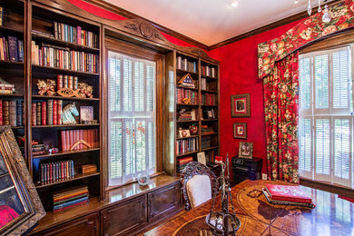 オースティンにある高級な広いヴィクトリアン調のおしゃれなホームオフィス・書斎 (赤い壁、自立型机、ライブラリー) の写真