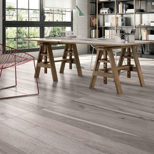 Mittelgroßes Industrial Arbeitszimmer mit Studio, grauer Wandfarbe, braunem Holzboden und freistehendem Schreibtisch in New York