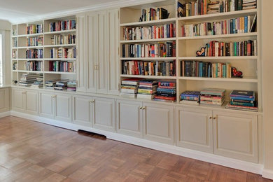 Imagen de despacho tradicional grande sin chimenea con biblioteca, paredes beige y suelo de madera en tonos medios